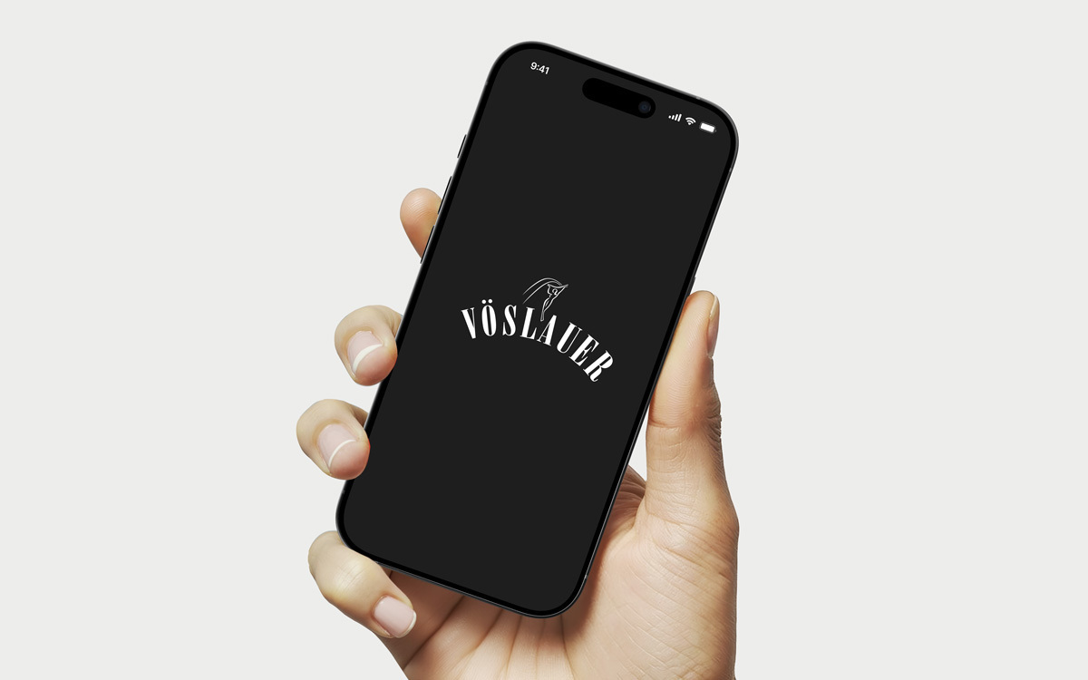 Smartphone in der Hand mit Vöslauer Logo am Screen